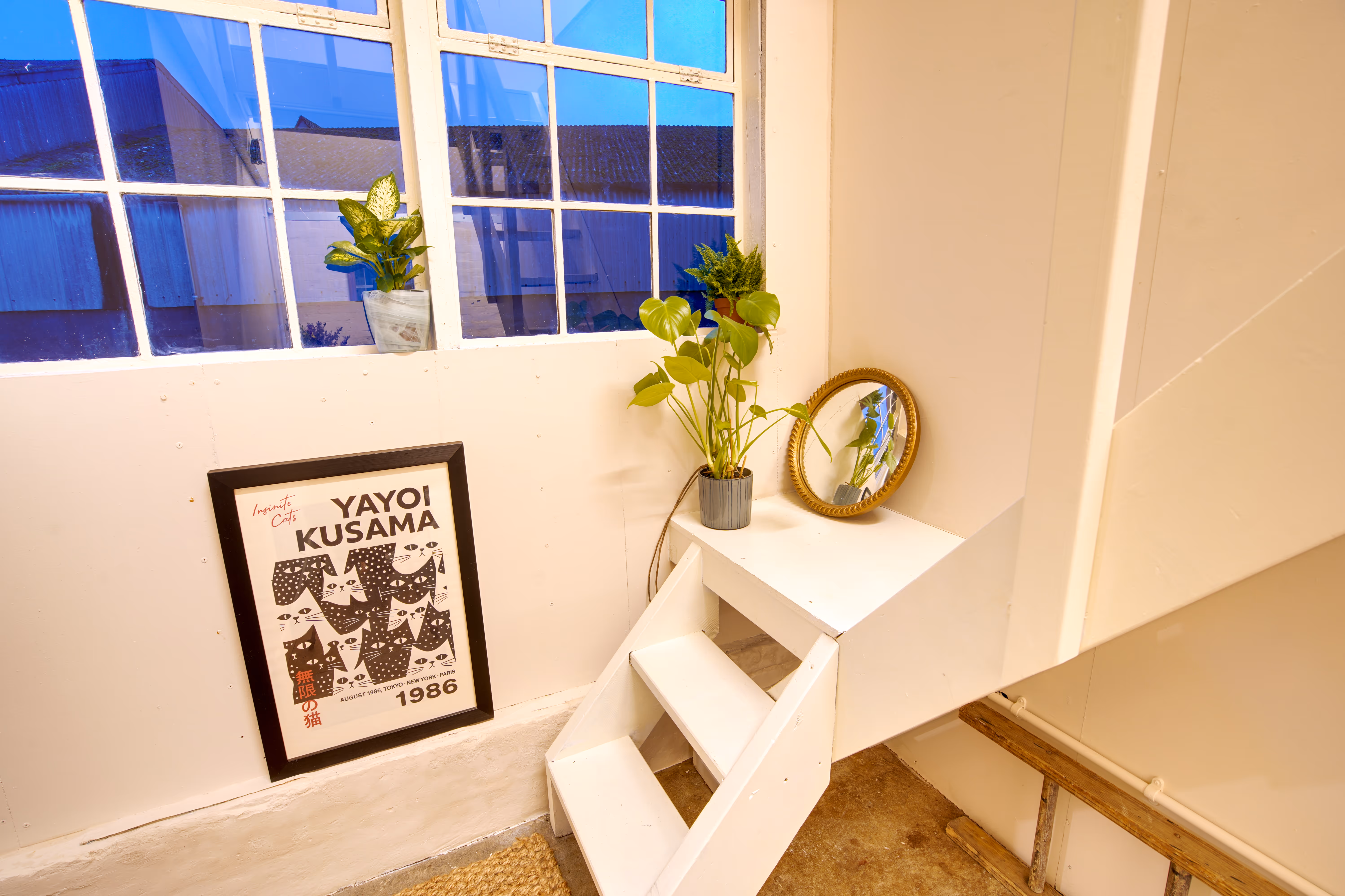 The corridor with stairs up to the mezzanine — bright, plants on the window sill.