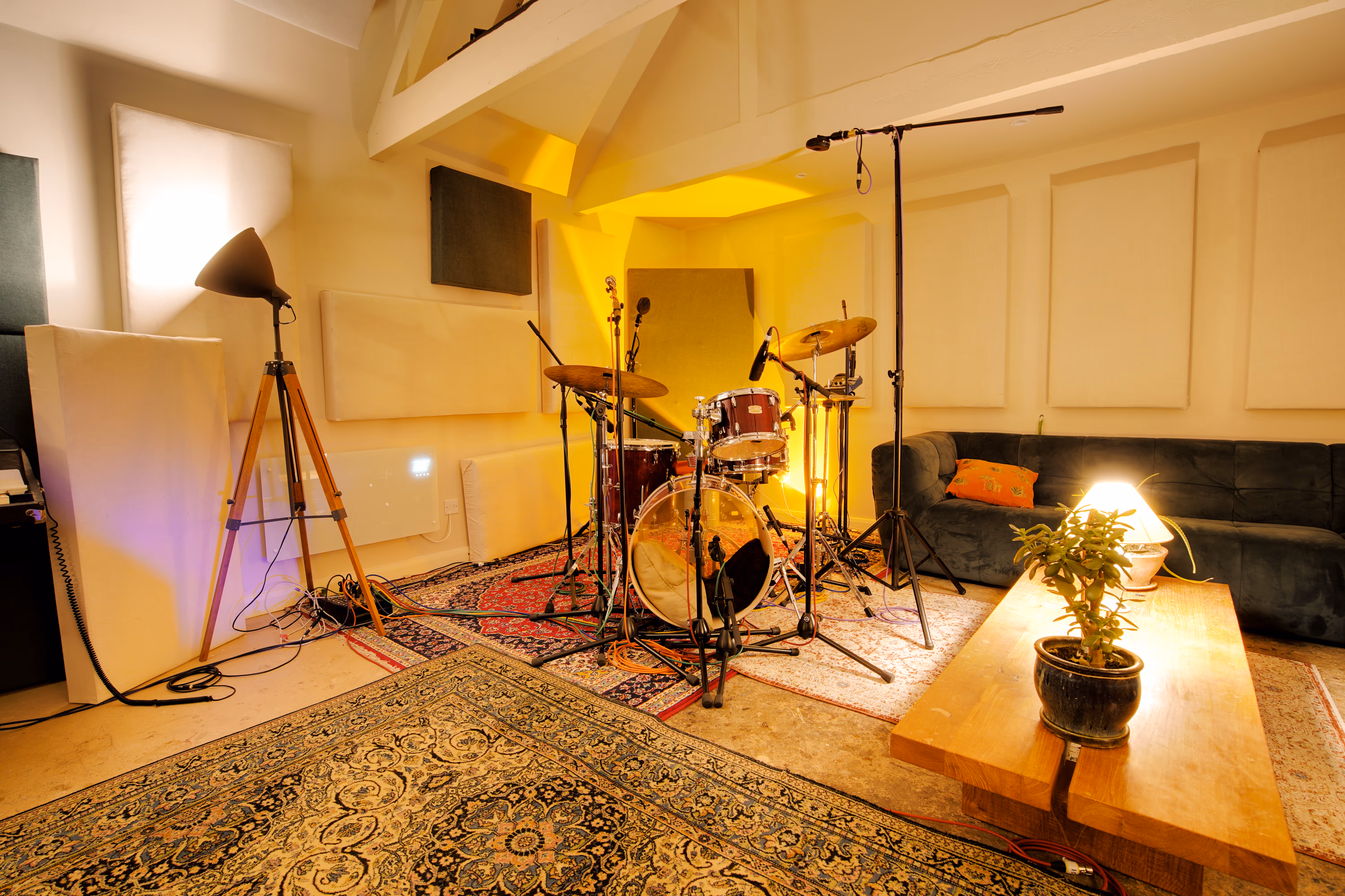 The live room set up for drums — kit, cymbals, mics, vintage rugs.