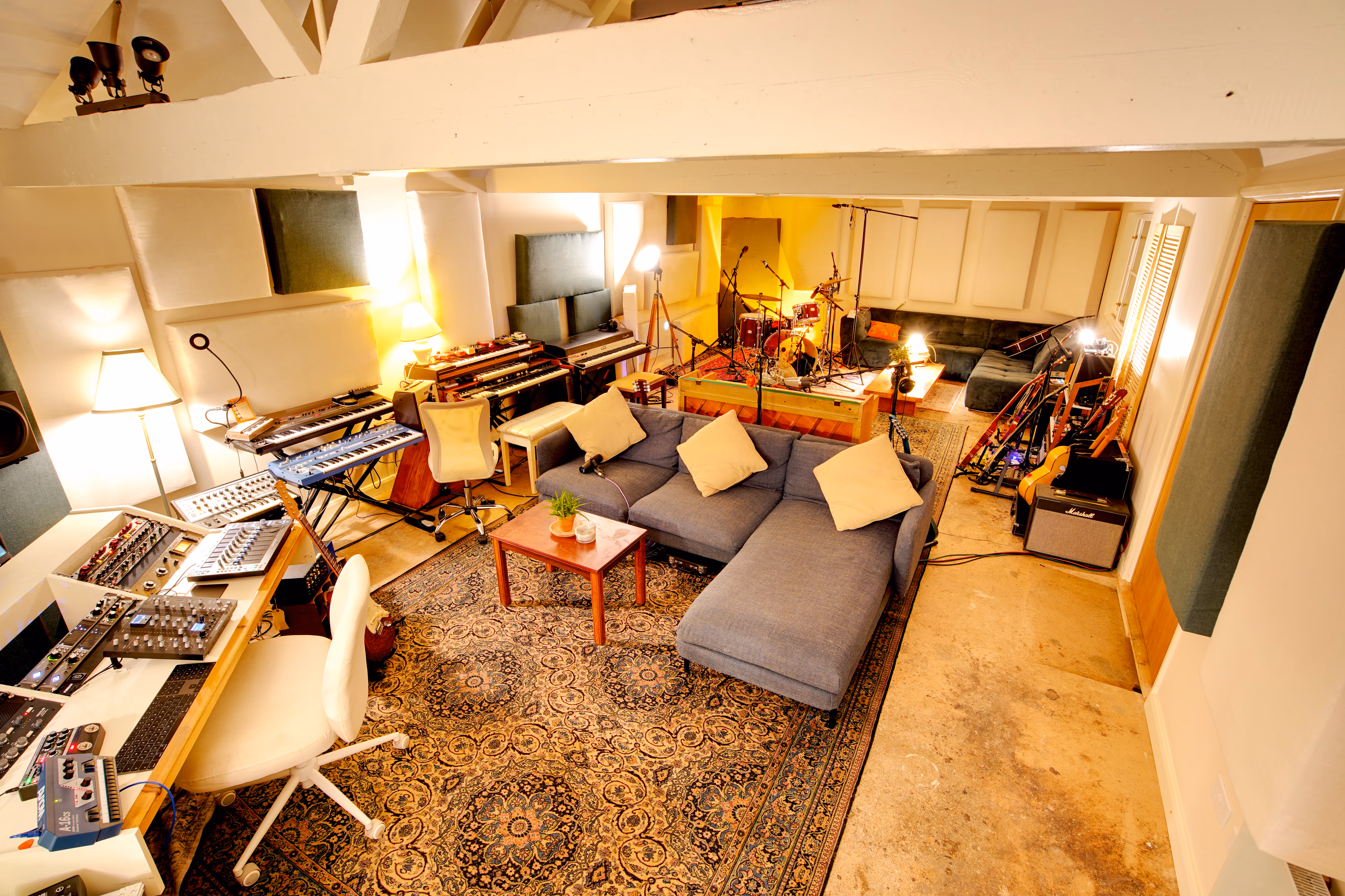 The main room of Beam Studios, photographed from above — sofa, mixing desk, instruments, Persian rug.